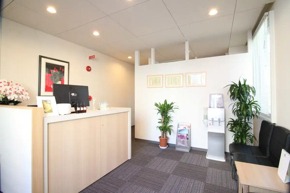 札幌クラーク治療院の、清潔感のある落ち着いた受付。観葉植物と間接照明が、お客様をリラックスできる空間でお迎えします。