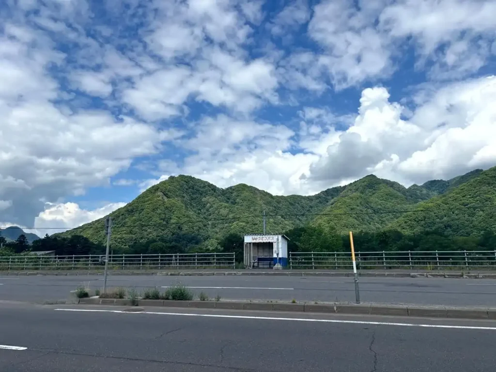 札幌市南区藤野付近の石山通の風景。じょうてつバス停と、遠くに見える山々。